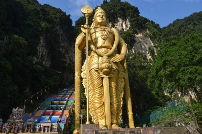 Large golden Murugan statue at Batu Caves, a famous Hindu pilgrimage site.