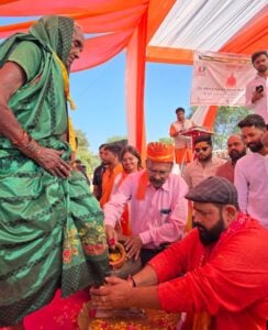 Hindu religious ceremony with priest and devotees performing rituals outdoors.