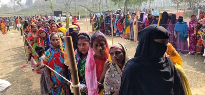Women in colorful traditional attire standing in line at Hindu festival.