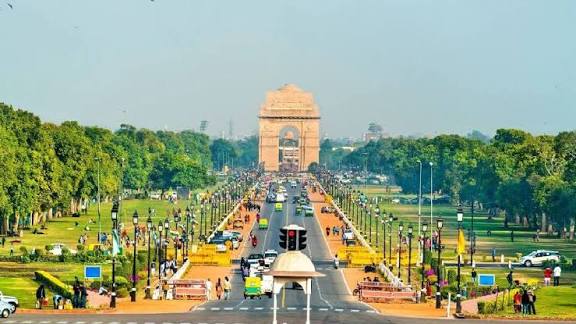 Iconic India Gate monument with busy road and greenery in New Delhi.