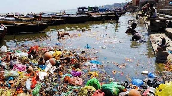 Polluted river in India with floating trash, showing environmental challenges and sanitation issues.