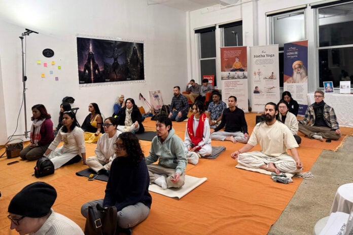 People meditating during Hindu spiritual event at night.