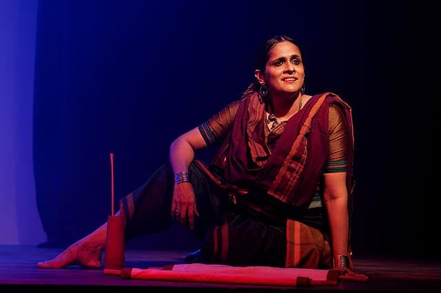 Woman performer in traditional attire portraying a scene from the Ramayana on stage.