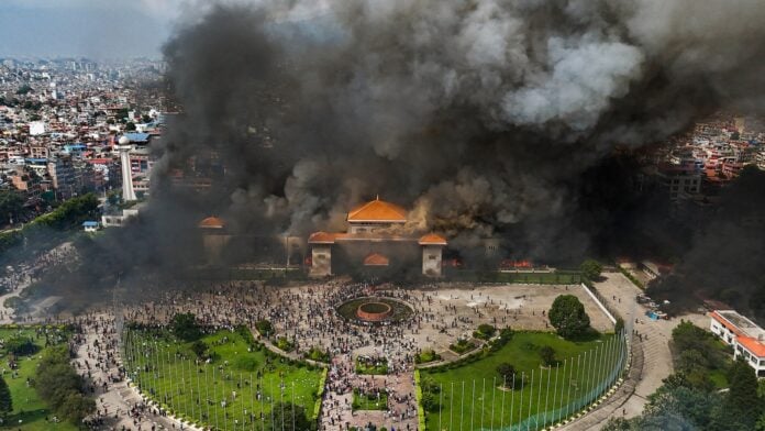 Large fire and smoke at a historic site during Nepal protests, reflecting social unrest.