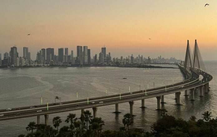 Modern Mumbai skyline with a bridge over the water at sunset, symbolizing economic progress.