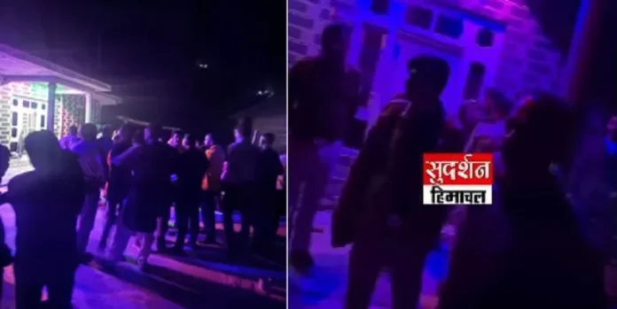 Crowd gathered at night in a dimly lit venue, illuminated by purple lighting.