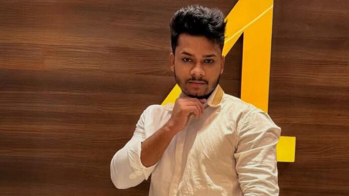 Young man posing in front of HinduPost logo, promoting Hindu culture.