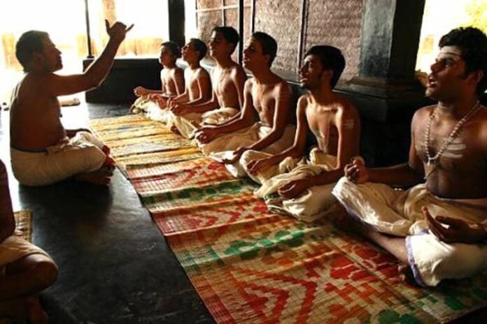 Hindu students sitting cross-legged on the floor during a traditional learning session.