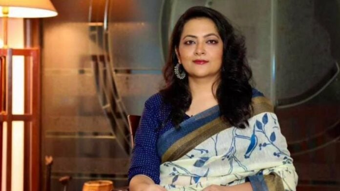 Hindu woman wearing saree with jewelry, indoor setting, cultural attire.