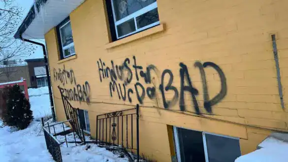 Graffiti on yellow wall with anti-Hindu messages and hate symbols.