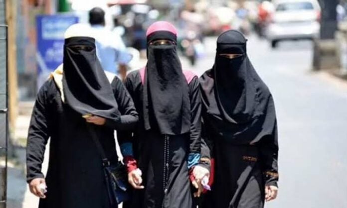 Women in black niqab walking on the street, covering faces, in urban setting.