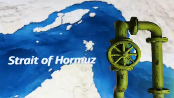 Close-up of green industrial pipeline valve against map of Strait of Hormuz.