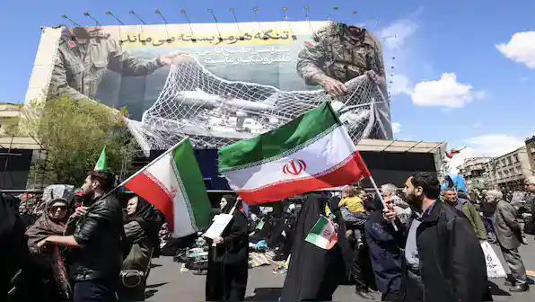 Protesters in Iran waving flags during a demonstration, symbolizing geopolitical tensions.