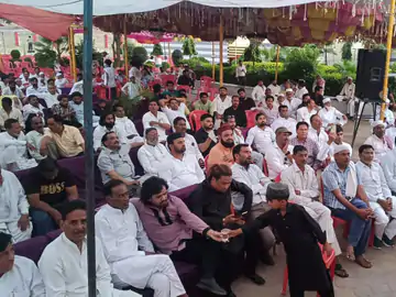 Large Hindu community gathering at outdoor event with attendees seated under tents.