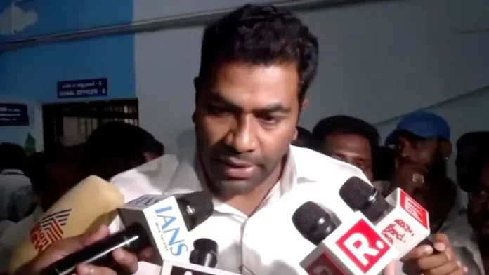 Hindu leader speaking to journalists surrounded by microphones and reporters.