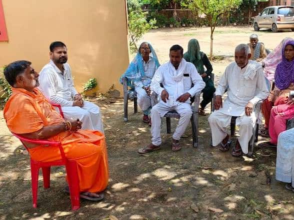Group of Indian men and women participating in a community meeting outdoors.