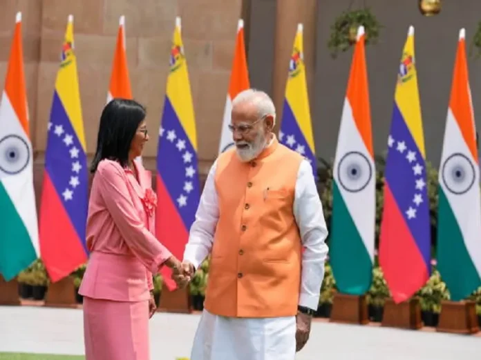 Indian and Venezuelan leaders exchanging greetings at international summit with flags in background.