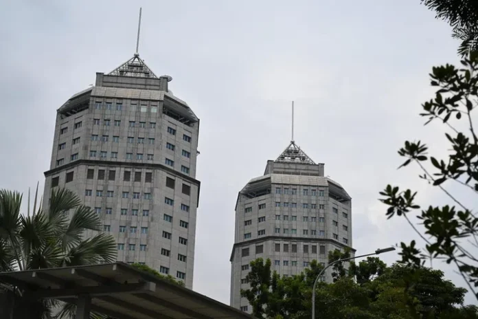 Twin skyscrapers in Singapore city skyline with trees in foreground.