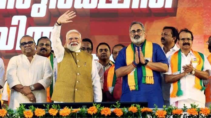 Indian political leaders on stage during rally with BJP flags and flowers.