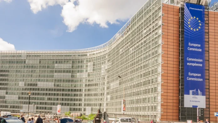 European Commission headquarters with EU flag and modern glass architecture.