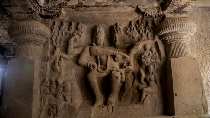 Carved stone sculpture of Lord Vishnu with multiple arms in a temple wall.