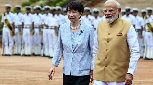 Indian and Japanese leaders walking together at a formal event with military personnel in background.