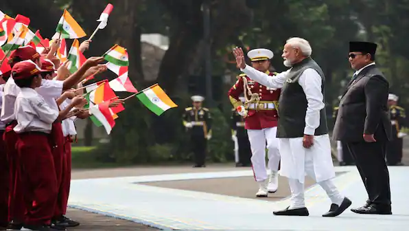 Prime Minister Modi greeting children holding Indian flags in a public event.