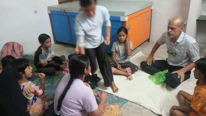 Children sitting on the floor with teacher in classroom, engaging in discussion.