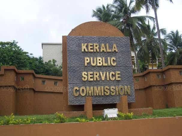 Signboard of Kerala Public Service Commission with palm trees in background.